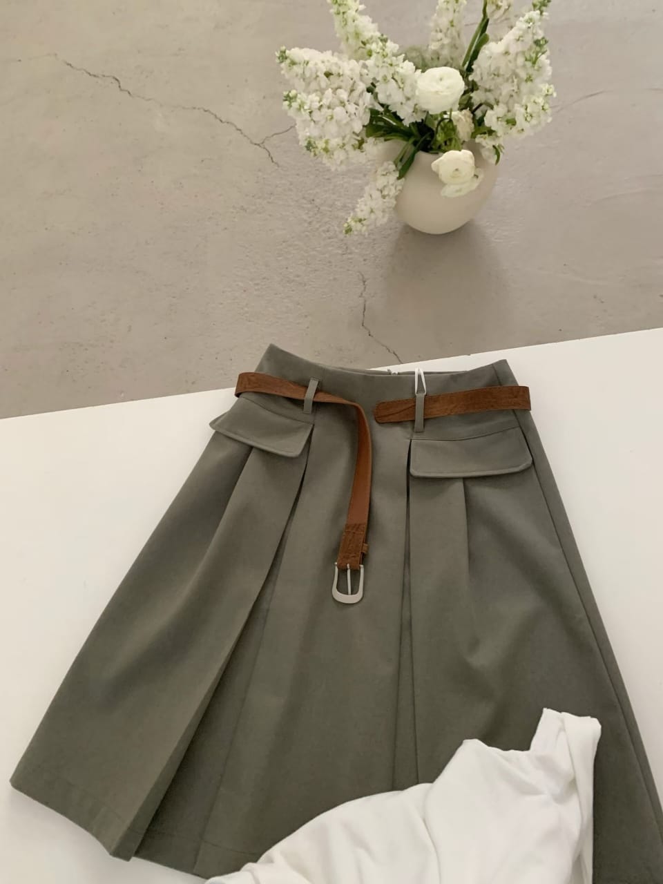 Olive belted pleated mini skirt flat lay