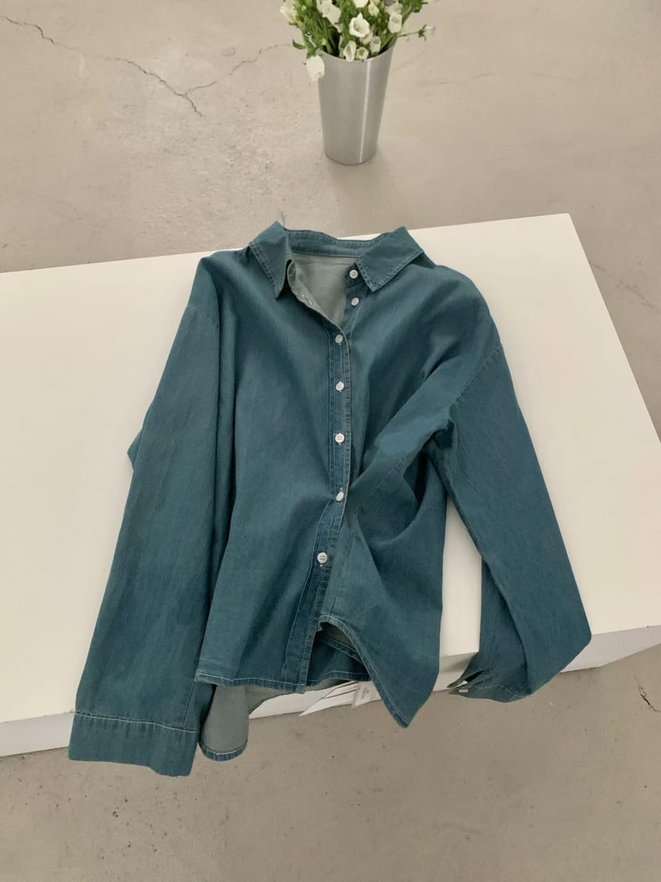 Deep teal denim shirt - flat lay on white surface