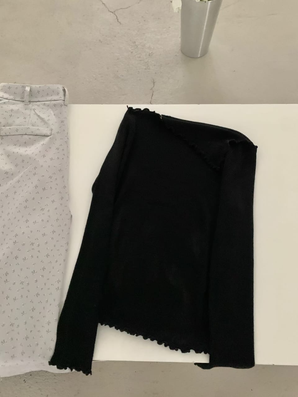 Black off-shoulder ribbed knit top and grey trousers - flat lay